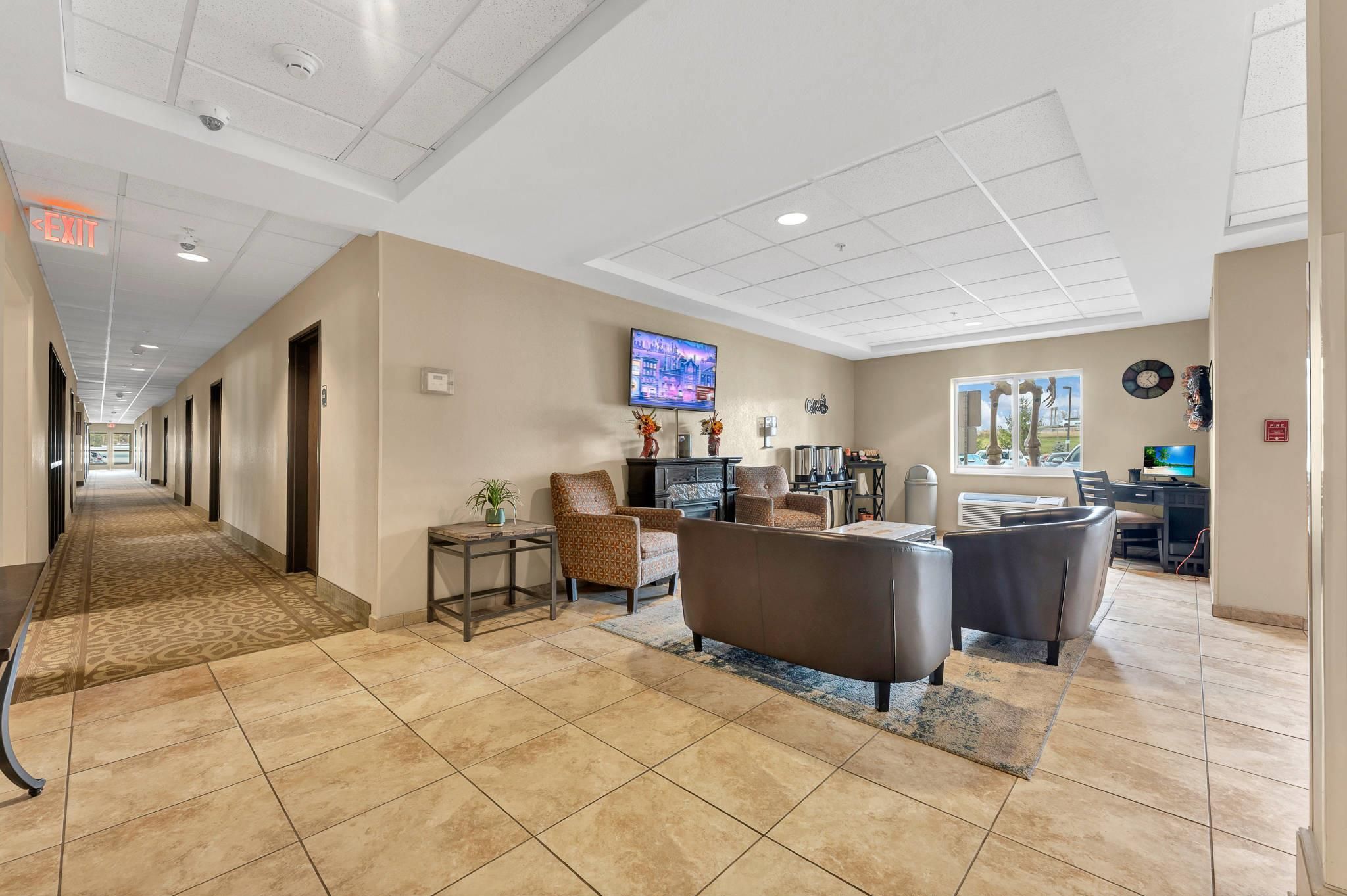 A hotel lobby with a long corridor, seating area, and a television.