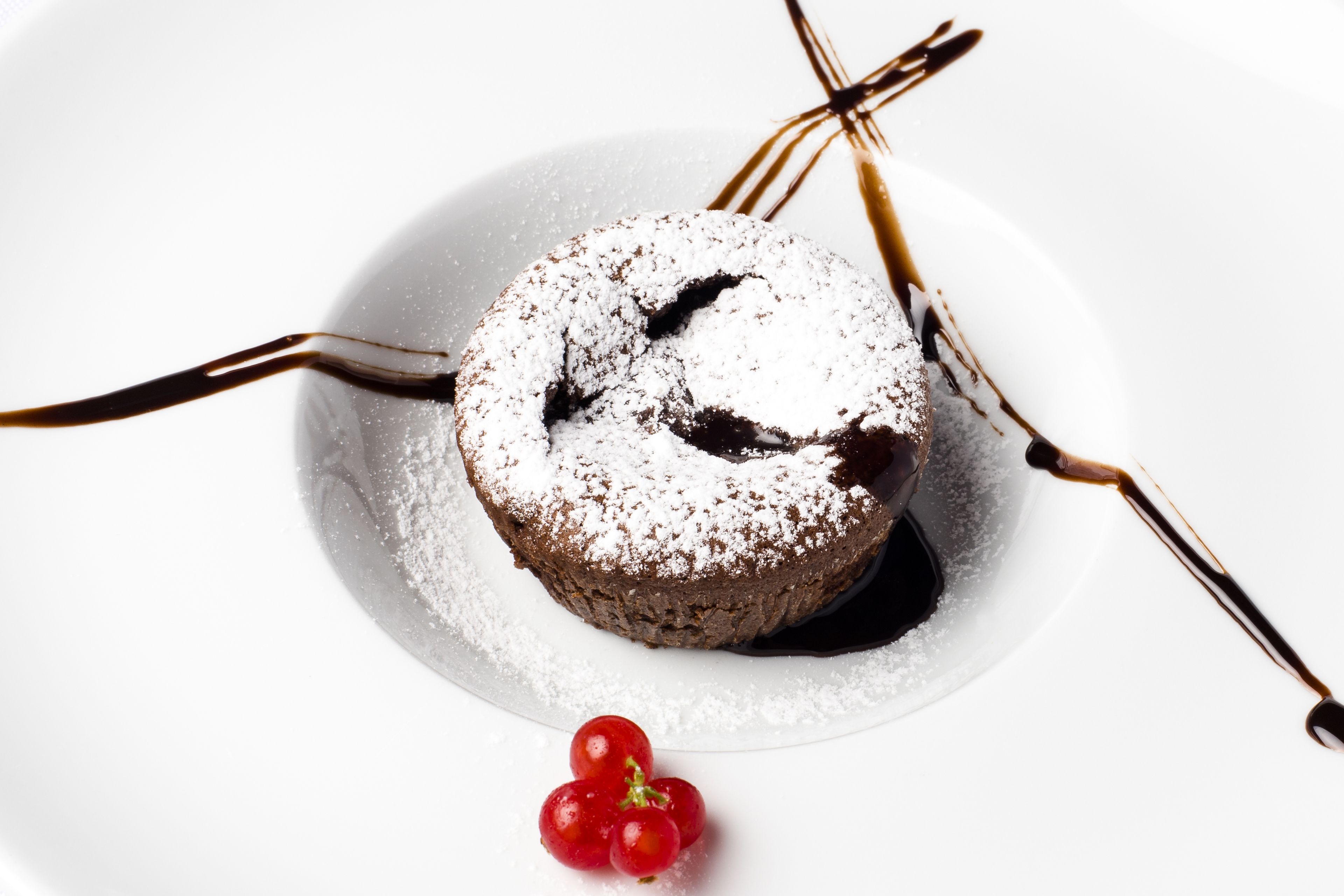 A dessert on a white plate with chocolate sauce and a dusting of powdered sugar.