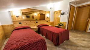A room with two beds, wooden walls, a mirror, and a wooden wardrobe. - Hotel Ristorante Alla Nave (Lavis)