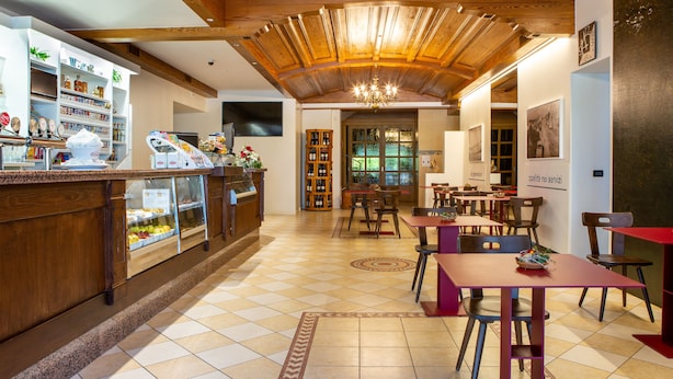 A restaurant with a wooden ceiling, tiled floor, and a variety of seating options including tables and chairs. - Hotel Ristorante Alla Nave (Lavis)