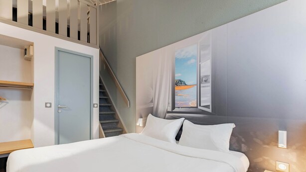 A hotel room with a bed, a desk, a wardrobe, and a staircase. - B&B HOTEL Calais Coquelles Tunnel sous la Manche (Coquelles)
