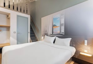 Una habitación de hotel con cama, escritorio, armario y una escalera.