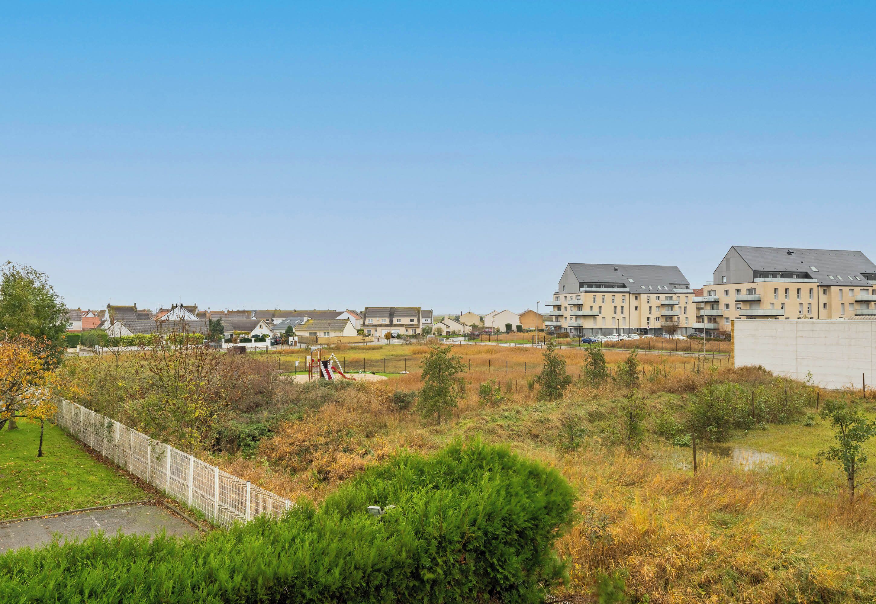 A residential area with houses, a playground, and a fenced field.
