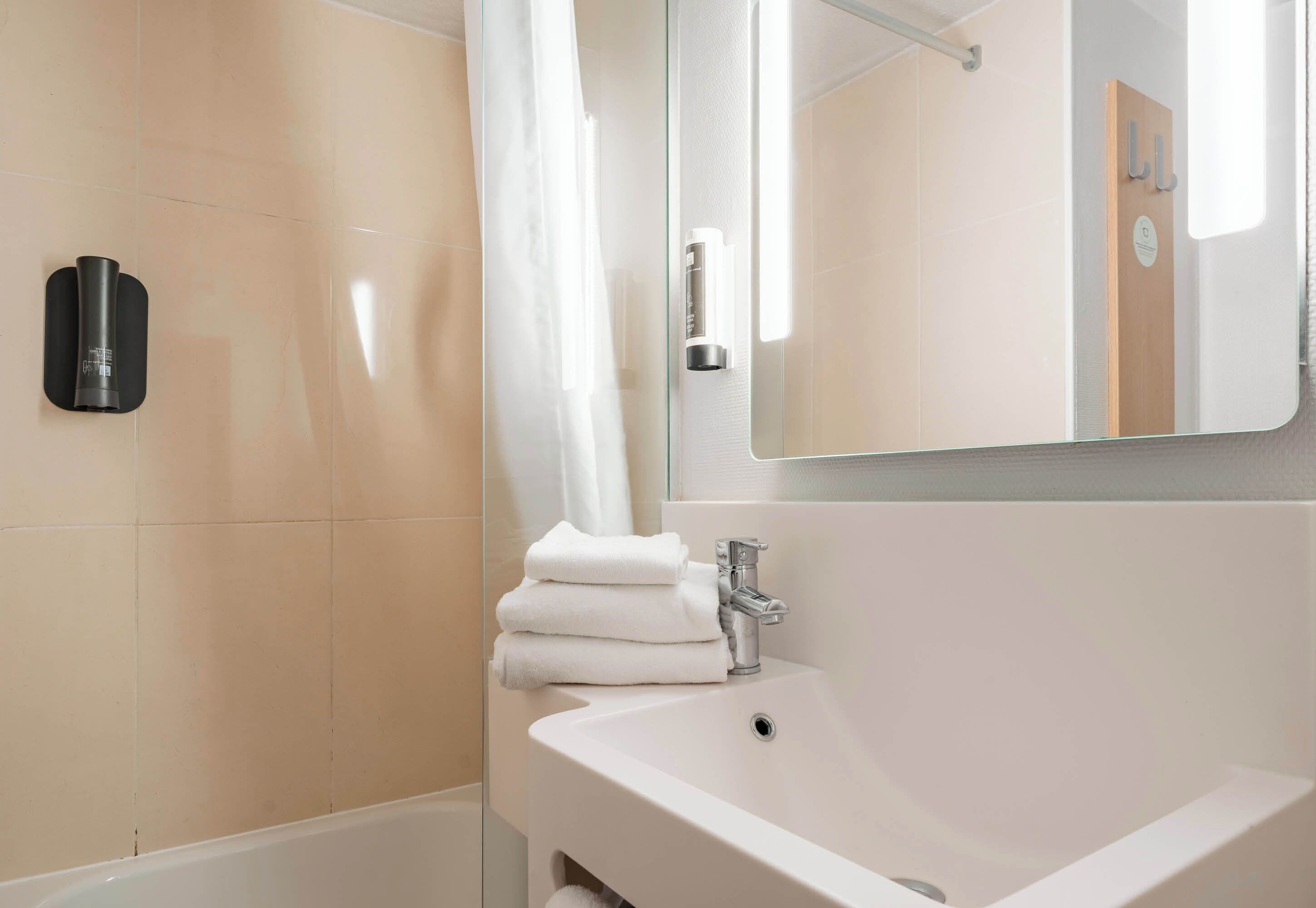 A modern bathroom with a white sink, a glass shower enclosure, and a mirror above the sink.