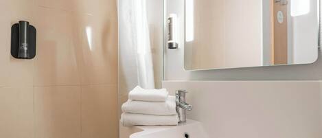 A modern bathroom with a white sink, a glass shower enclosure, and a mirror above the sink.