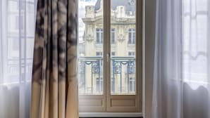 Una ventana con vista a un edificio de balcones ornamentales y una puerta.