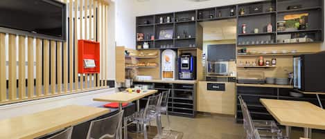 Un restaurante moderno con sillas de plástico transparente, mesas de madera y una variedad de alimentos y bebidas en estantes.