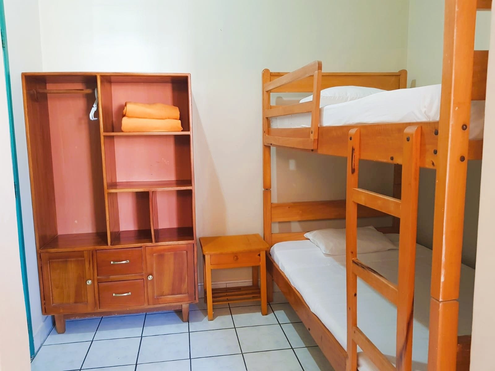 A bunk bed with a wooden wardrobe and a small table.