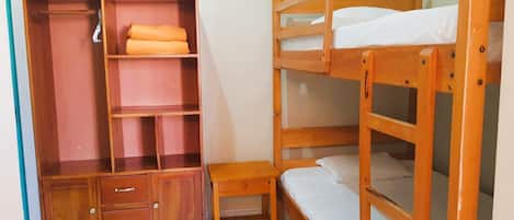 A bunk bed with a wooden wardrobe and a small table.