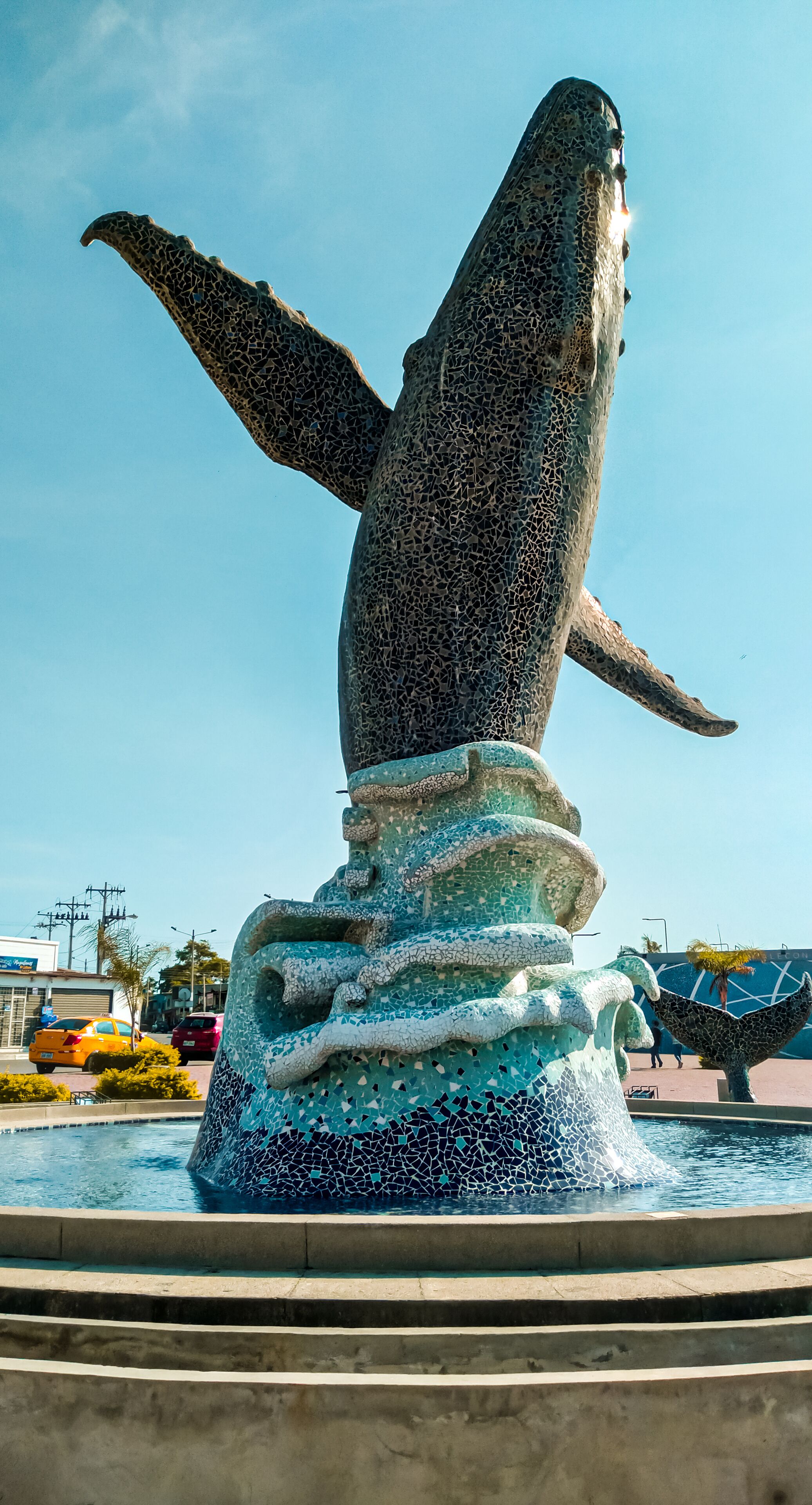 A whale statue with outstretched flippers, set in a fountain with a tiled base.