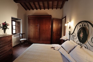Cozy retreat with a comfortable bed, wooden wardrobe, and a nightstand with a lamp.