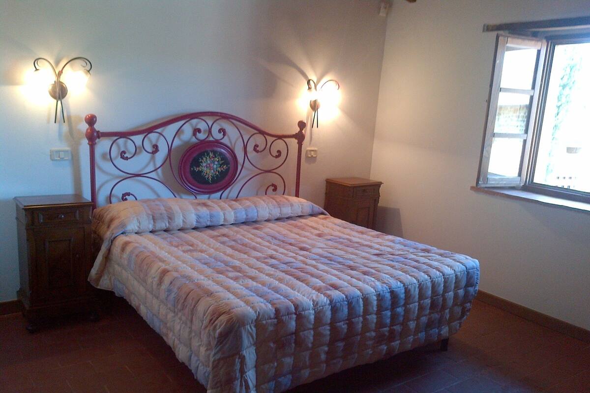 A bedroom with a bed, a nightstand, a dresser, and a window.