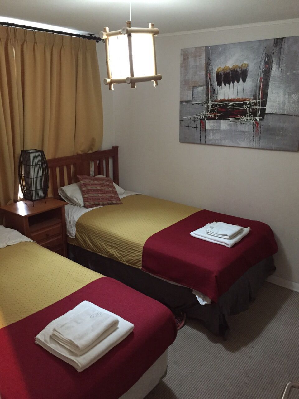 Une chambre d’hôtel avec deux lits, une tête de lit en bois, une table de chevet avec une lampe et un tableau au mur.