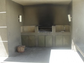 Compact kitchen area with oven and sink, featuring ample storage and a convenient stool.