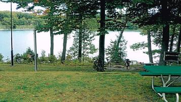 Un parque junto al lago con mesas de picnic y un banco.