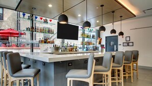 A bar area with a counter, bar stools, and shelves of bottles. - Hyatt House Chicago/Evanston (Evanston)