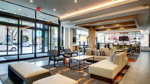 A modern lobby with seating areas, a bar, and large windows offering views of the street. - Hyatt House Chicago/Evanston (Evanston)