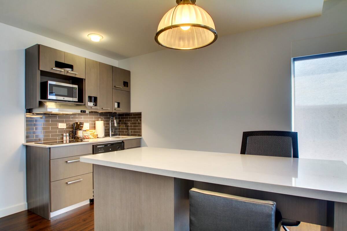 A modern kitchen with a built-in microwave, dishwasher, and a large island with seating.