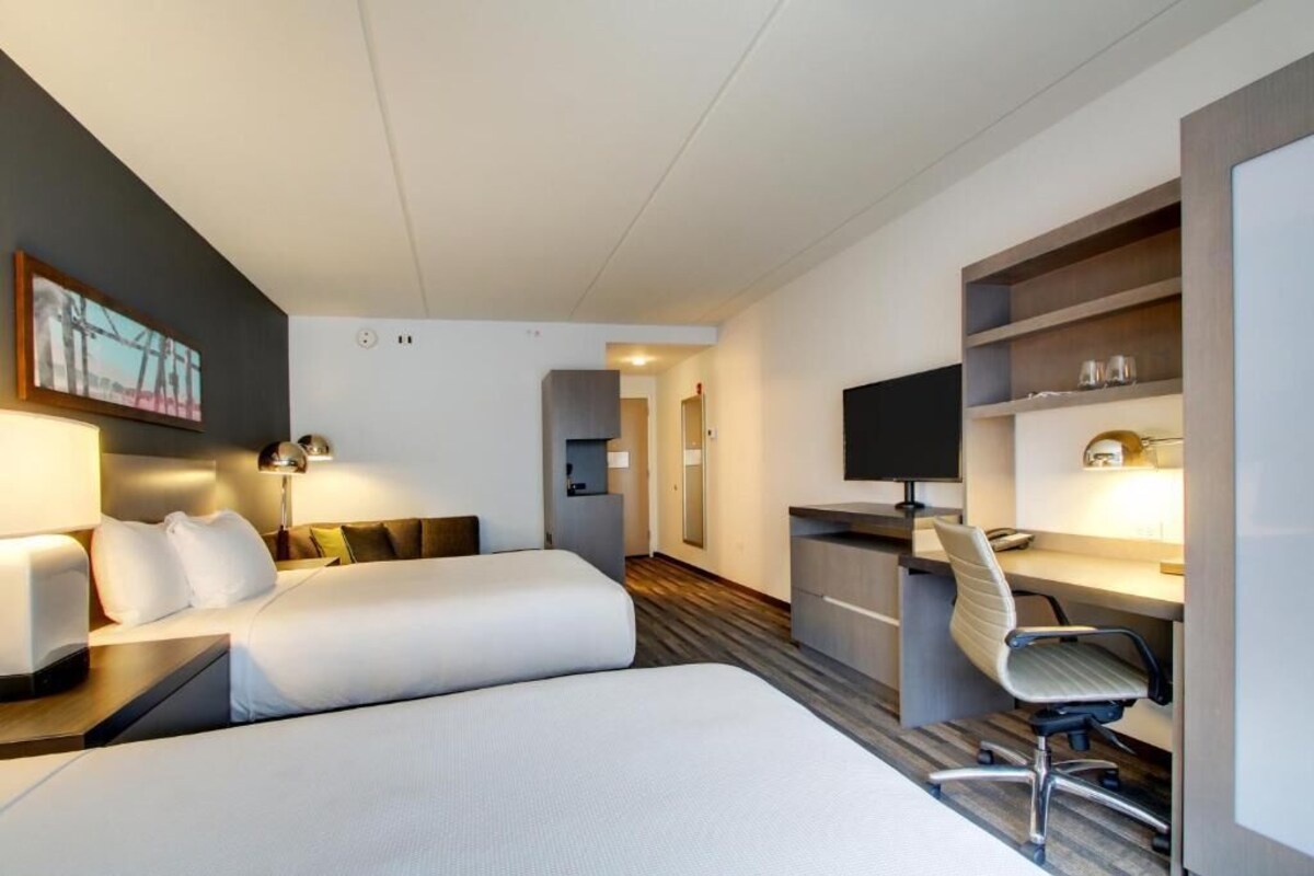 Hotellihuone, jossa on kaksi sänkyä, työpöytä, tuoli, televisio ja kirjahylly.