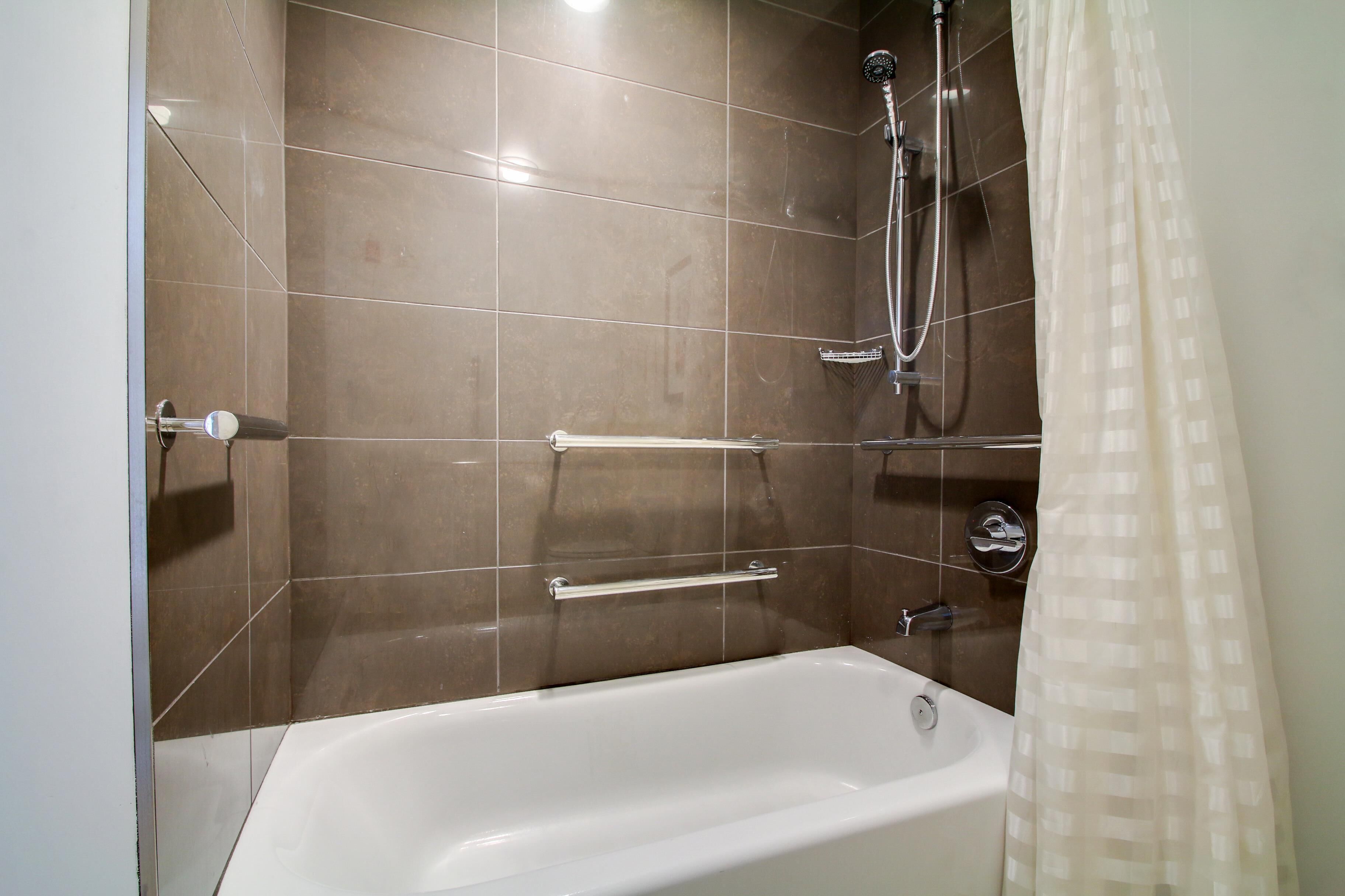 A bathroom with a bathtub, shower, and tiled walls.