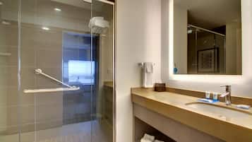 A modern bathroom with a glass shower enclosure, a sink with a mirror, and a towel rack.