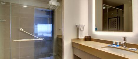 A modern bathroom with a glass shower enclosure, a sink with a mirror, and a towel rack.