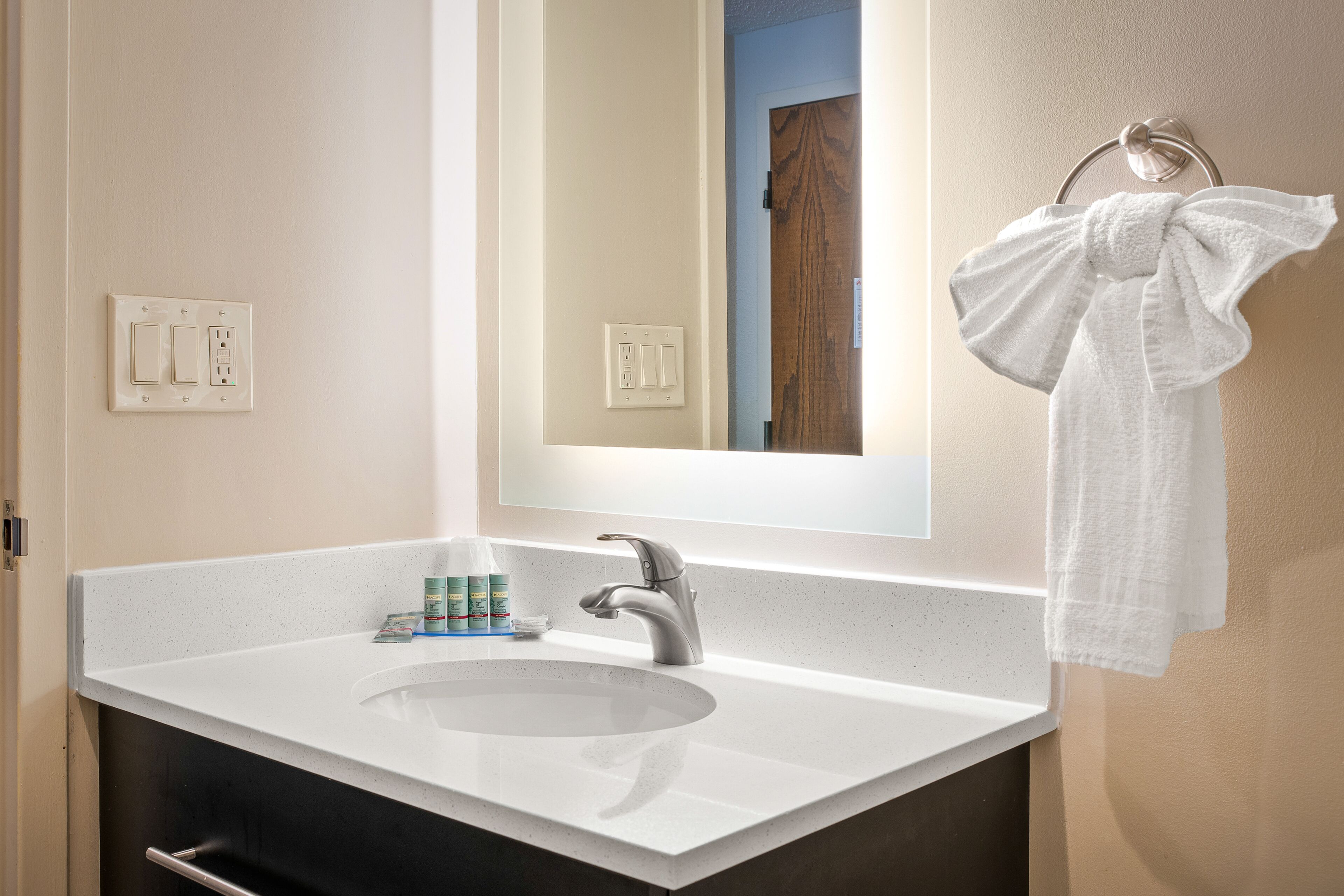 A bathroom with a white sink, a mirror, and a towel hanging on a towel rack.