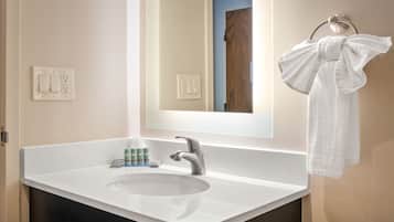 A bathroom with a white sink, a mirror, and a towel hanging on a towel rack.