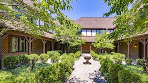A courtyard with a central fountain, surrounded by neatly trimmed bushes and trees.