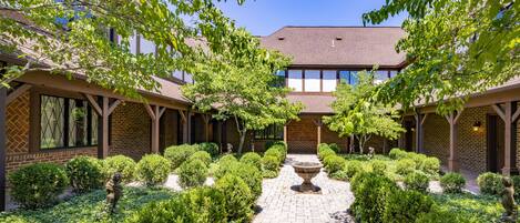 A courtyard with a central fountain, surrounded by neatly trimmed bushes and trees.