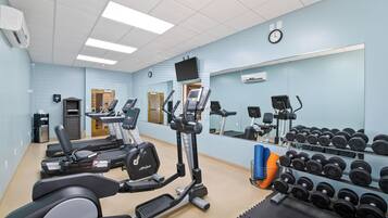 A gym with treadmills, elliptical machines, and a rack of dumbbells.