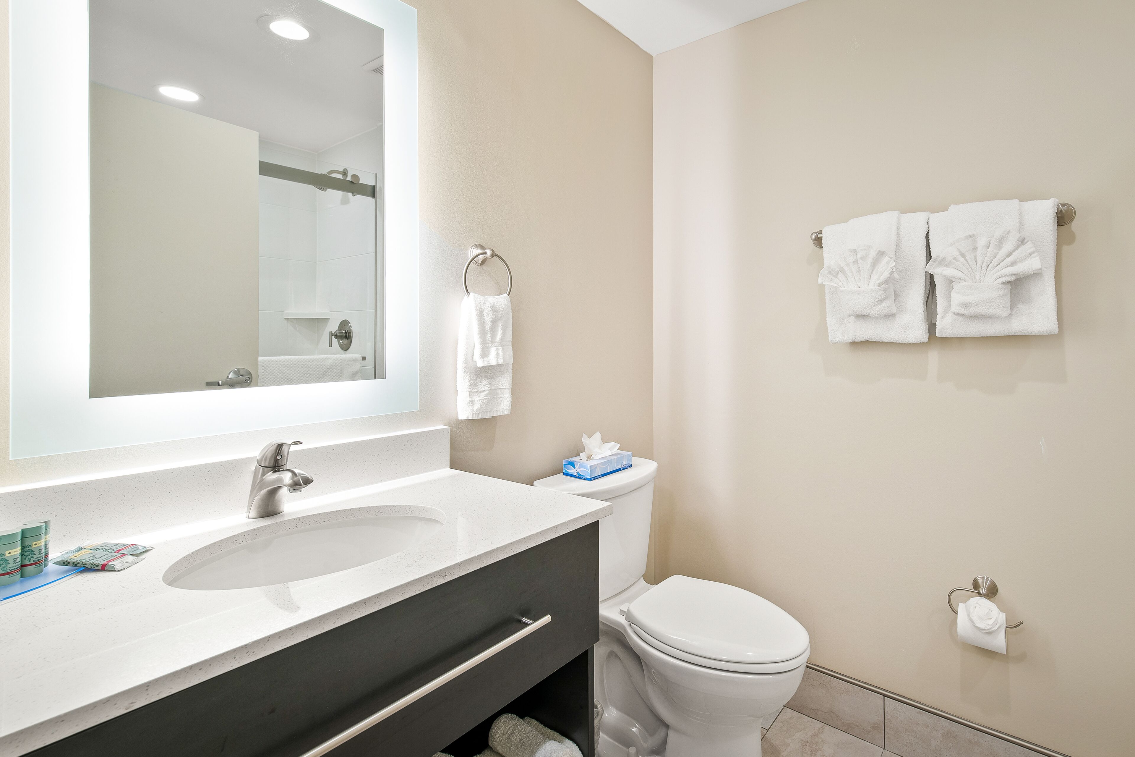 A bathroom with a sink, mirror, toilet, and towel rack.