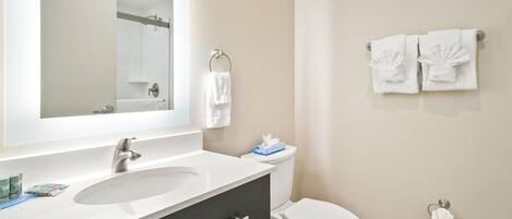 A bathroom with a sink, mirror, toilet, and towel rack.