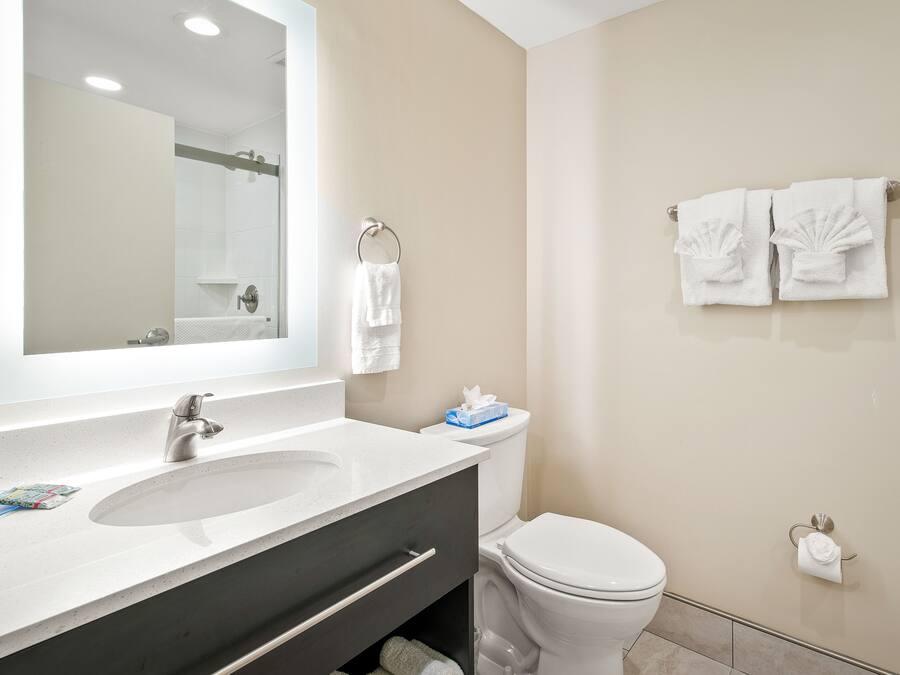 A bathroom with a sink, mirror, toilet, and towel rack.