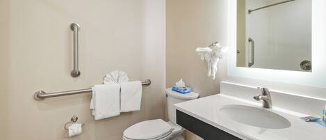 A modern bathroom with a white toilet, a sink with a mirror above it, and a handrail on the wall.