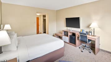 Une chambre d’hôtel équipée d’un lit, d’un bureau, d’une chaise, d’une télévision et d’une petite kitchenette.