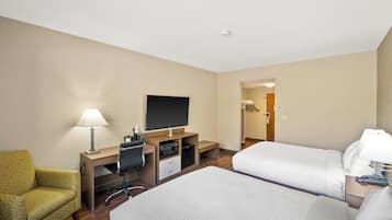 Una habitación de hotel con dos camas, un escritorio con computadora, un televisor y una silla.