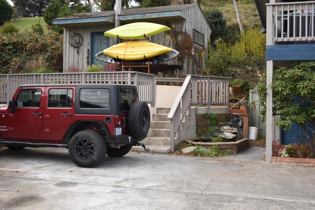A red off-road vehicle parked in front of a house with a wooden deck and a set of stairs leading to a porch.