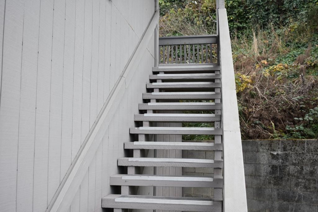 Una escalera de madera con barandilla de metal que conduce a una puerta.