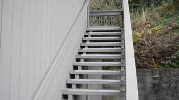 Una escalera de madera con barandilla de metal que conduce a una puerta.