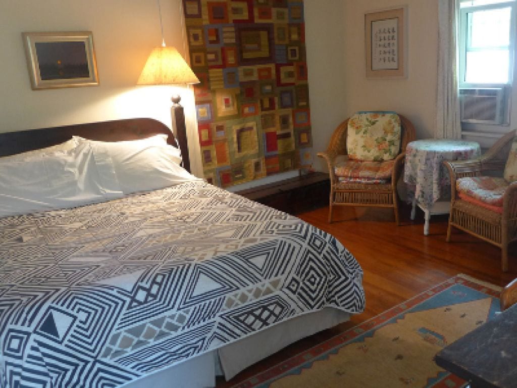 A bedroom with a large bed, a chair, a small table, and a colorful wall.