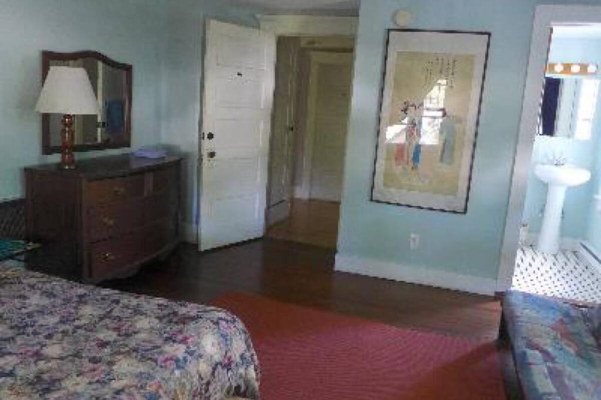 Ein Schlafzimmer mit Bett, Schminktisch und einer Tür zu einem anderen Raum.