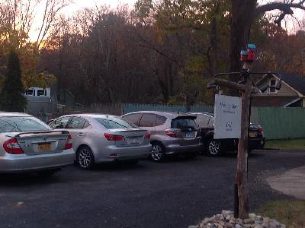 Un parking avec plusieurs voitures garées et un panneau fixé à un poteau.