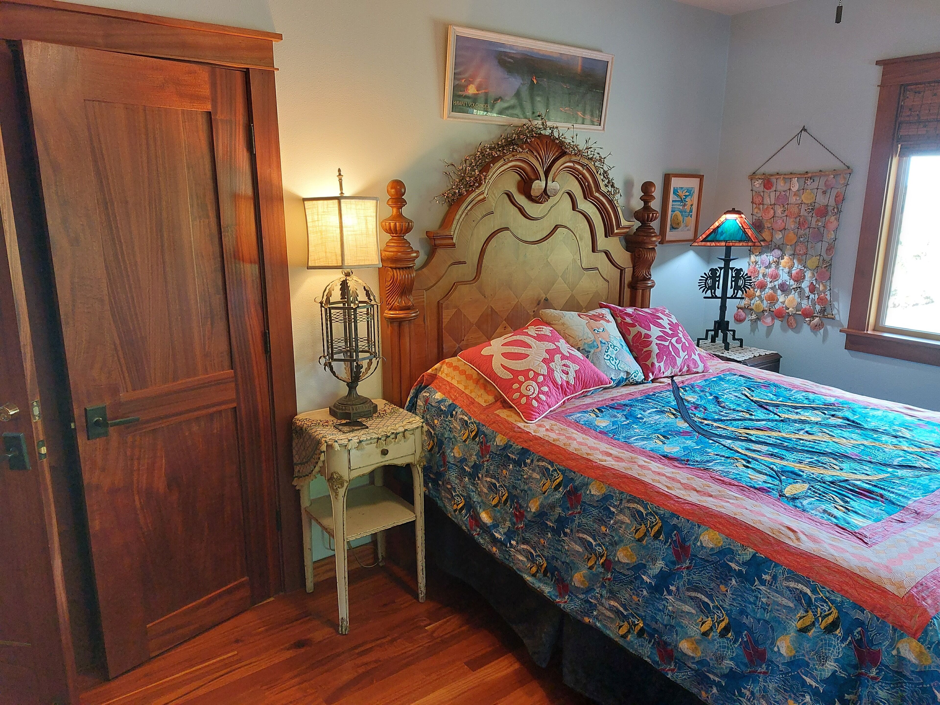 Un dormitorio con cama de madera, mesita de noche, lámpara, silla y una puerta.