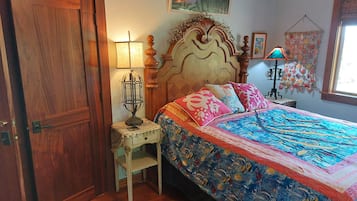 A bedroom with a wooden bed, a nightstand, a lamp, a chair, and a door.