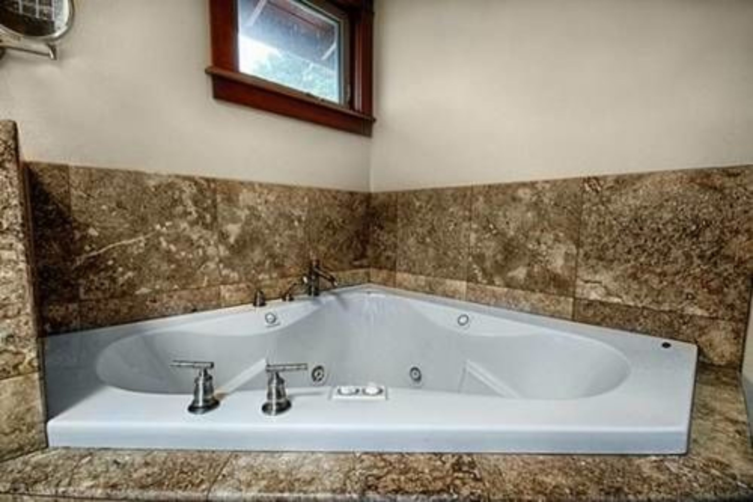 A large freestanding bathtub in a bathroom with granite tiles.