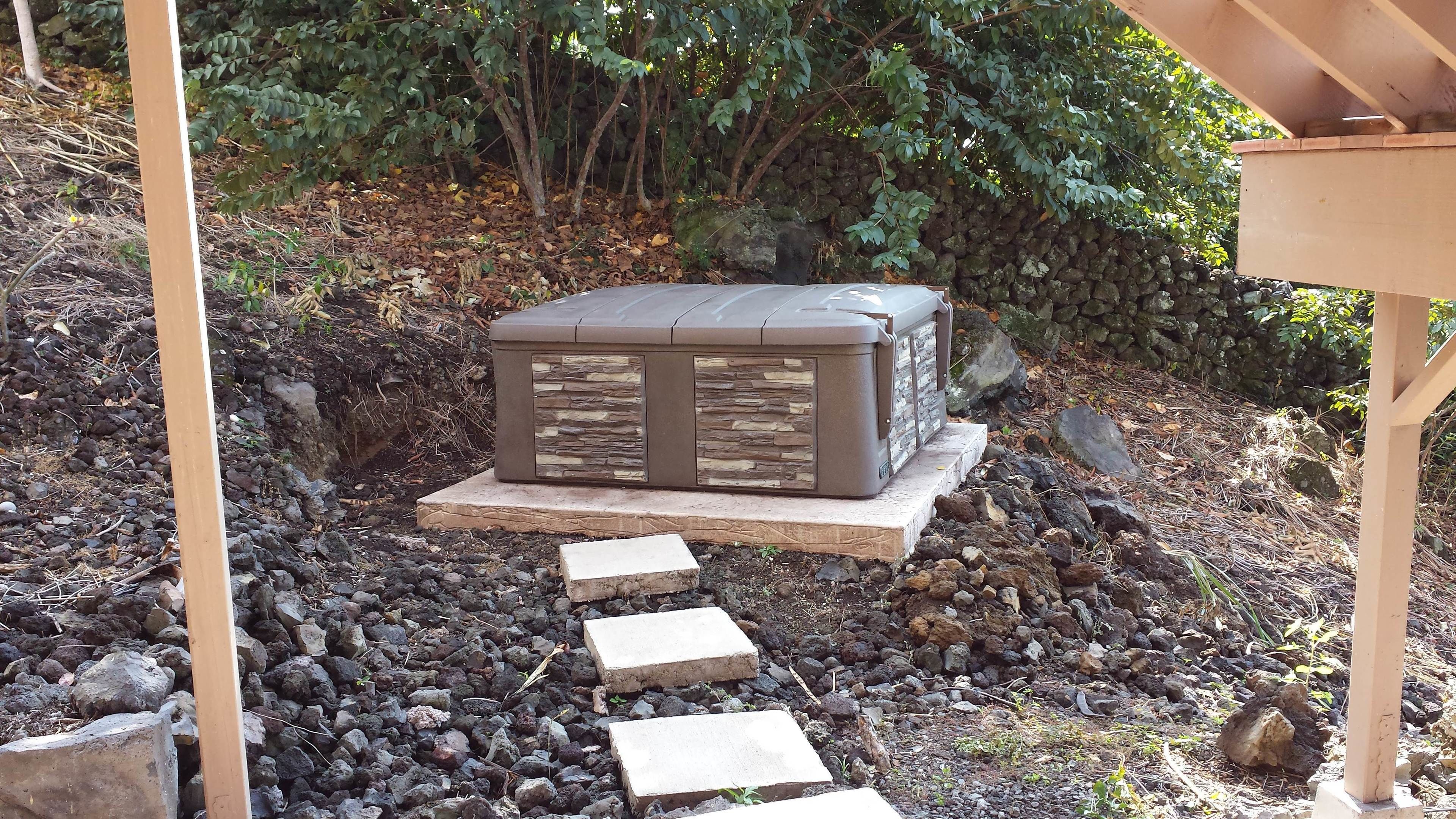Estructura de piedra con calentador integrado, rodeada por un muro de piedra y una terraza de madera.