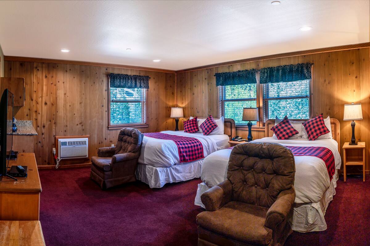 A room with two beds, a chair, a desk, and a window with curtains.