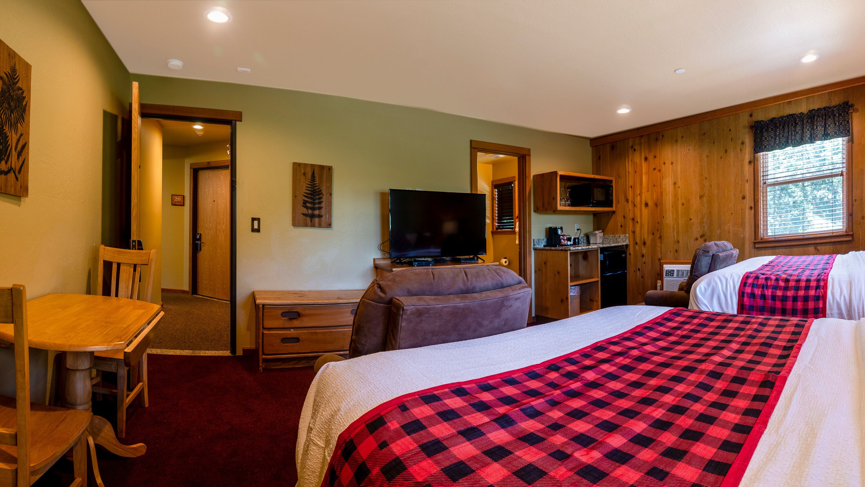 A hotel room with two beds, a television, a desk, and a chair.