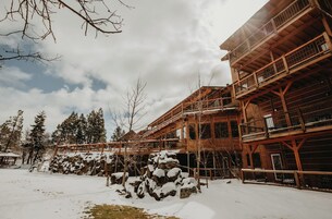 Un edificio de madera con varios balcones y suelo cubierto de nieve.